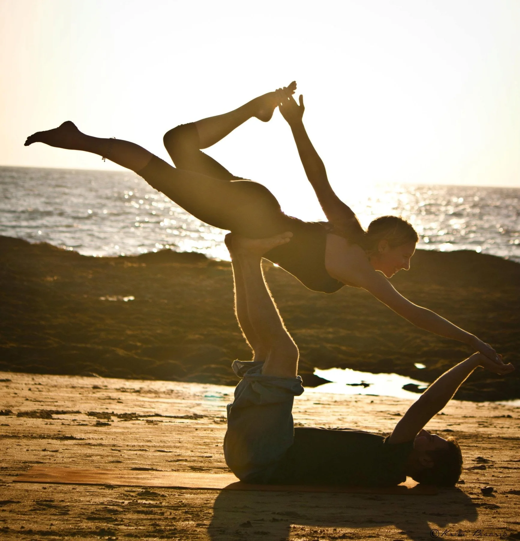 Acro yoga silhouetted against the sunset on a beach