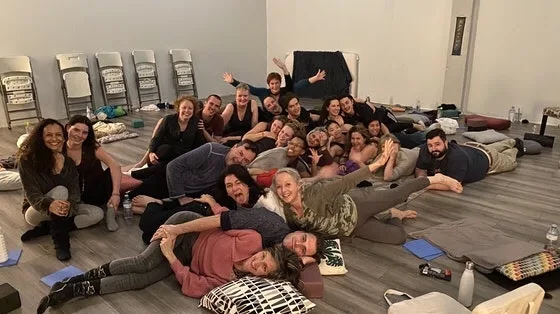 A HeartWise circle: some thirty people piled together, smiling, on the floor of a studio after a workshop