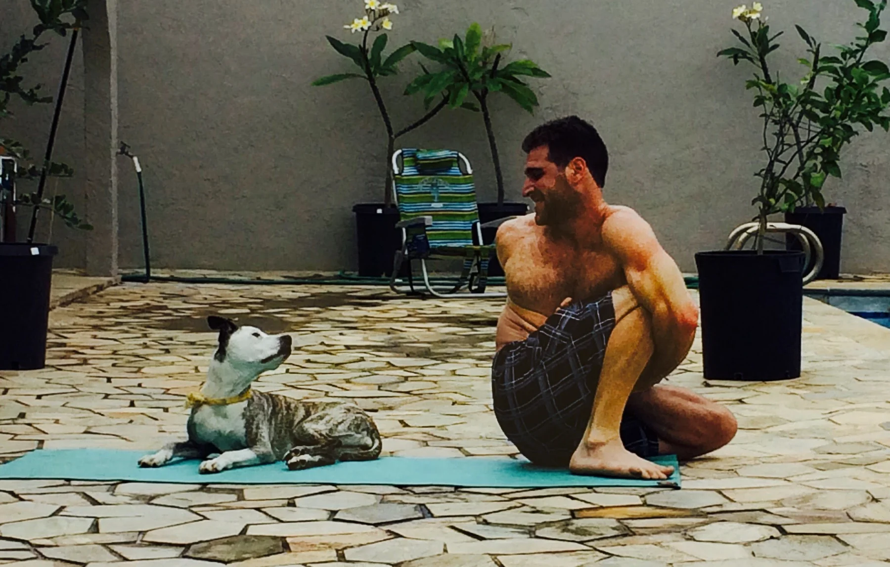 A deep squat on a mat on a stone patio, a dog lying alongside