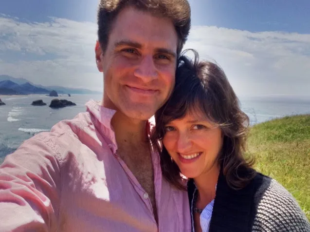 A selfie with a companion on a grassy headland above the sea, sea stacks behind