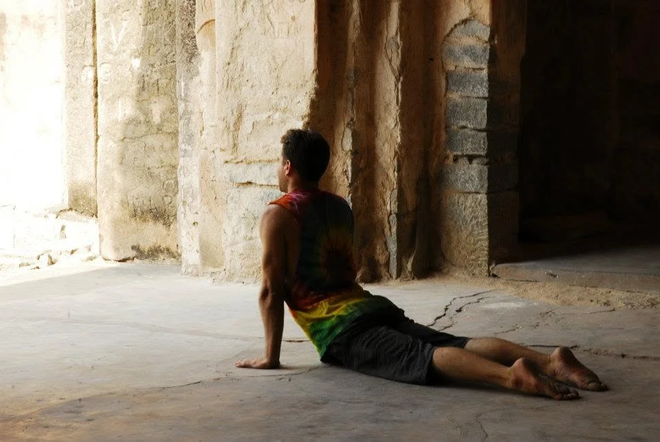 Sitting on the stone floor of an old pillared temple in India, legs stretched out in the shade