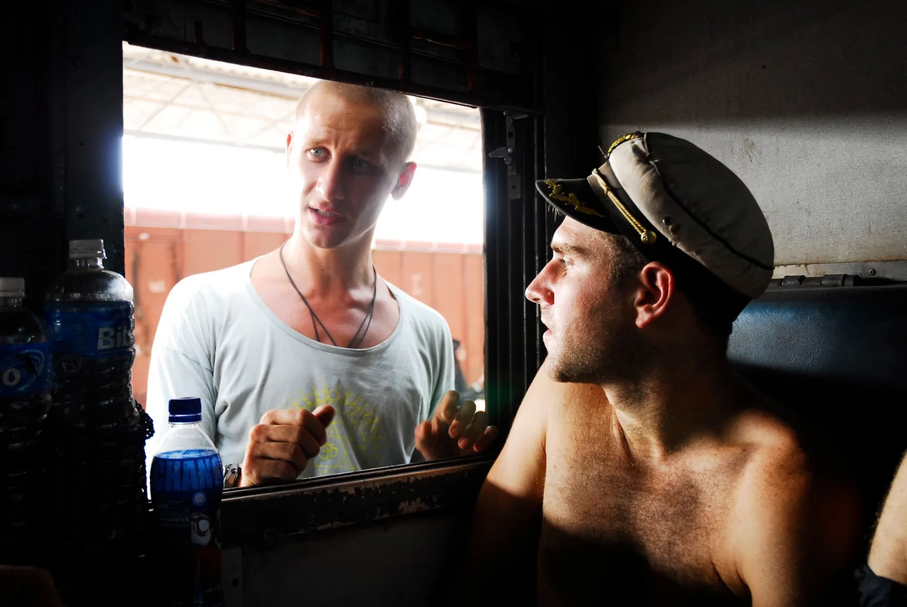 In a captain’s hat in a train compartment, talking with a fellow traveler through the open window